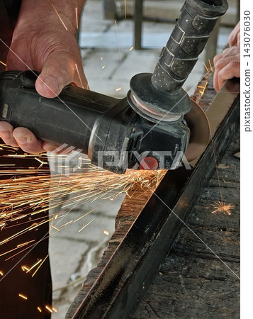 Cutting metal with an angle grinder, producing bright sparks. Cutting metal with an angle grinder, producing bright sparks. 143076030