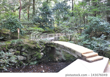 The Chitose Bridge in Kenrokuen Garden, spanning a moss-covered grove of trees. The Chitose Bridge in Kenrokuen Garden, spanning a moss-covered grove of trees. 143076049