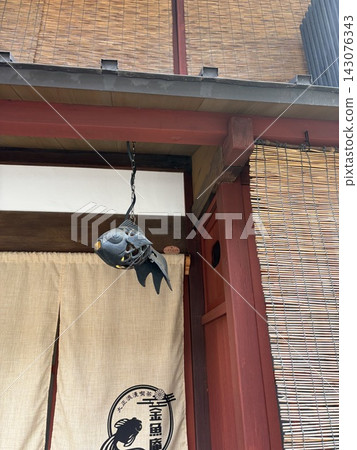傳統聯排別墅的屋簷下懸掛著金魚裝飾品和暖簾。 傳統聯排別墅的屋簷下懸掛著金魚裝飾品和暖簾。 143076343