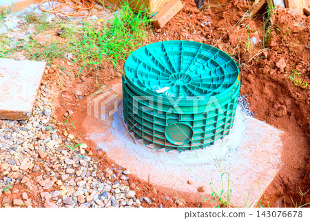 Green septic tank drainage utility structure is placed in ground at construction site among soil gravel. Green septic tank drainage utility structure is placed in ground at construction site among soil gravel. 143076678