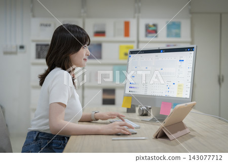 一位年輕的女設計師正在電腦前工作。 143077712