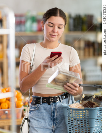 Girl inspects oyster mushrooms, photographs QR code on label by smartphone Girl inspects oyster mushrooms, photographs QR code on label by smartphone 143078523