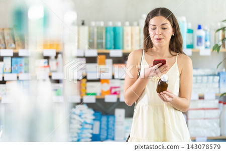 Woman scans cough syrup on her phone at pharmacy Woman scans cough syrup on her phone at pharmacy 143078579