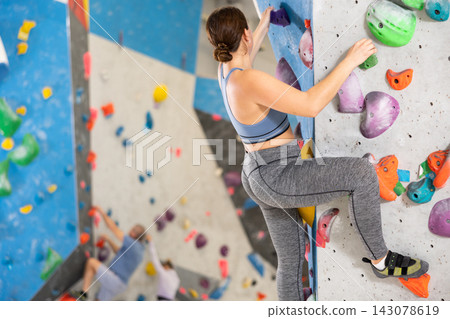 Young woman practicing rock climbing on climbing wall Young woman practicing rock climbing on climbing wall 143078619