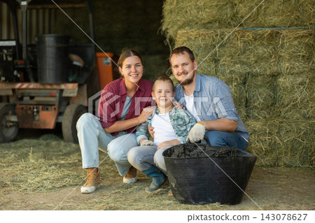 Man, woman and boy with bucket of hay in barn 143078627