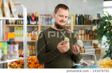 man chooses canned food. 143078785