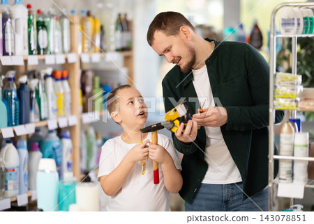 Schoolboy son and dad are choosing hand tools in store Schoolboy son and dad are choosing hand tools in store 143078851