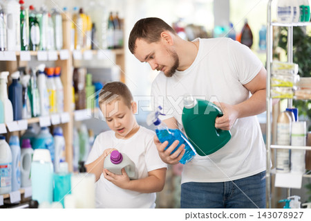 Young man and boy choosing detergent in store Young man and boy choosing detergent in store 143078927