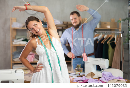 Two young seamstresses doing exercises during break Two young seamstresses doing exercises during break 143079083