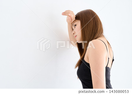 一名女子靠在牆上,一手扶著額頭。 一名女子靠在牆上,一手扶著額頭。 143080053