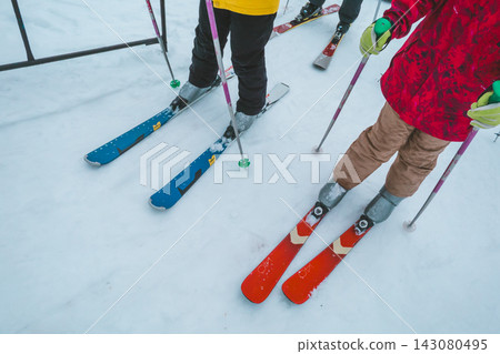 滑雪場裡,一對母女排隊等候纜車,她們的腳在雪道上若隱若現。 滑雪場裡,一對母女排隊等候纜車,她們的腳在雪道上若隱若現。 143080495