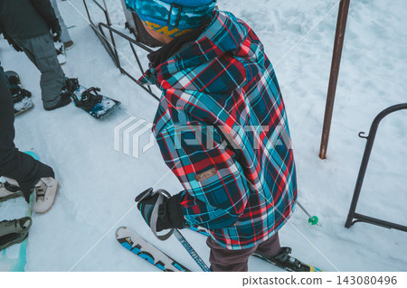 一名 12 歲男孩在滑雪場排隊等候纜車時，背對著鏡頭。 143080496