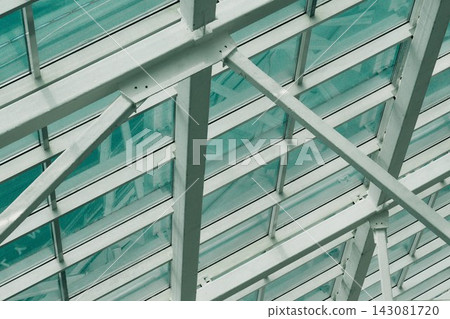 interior shot focusing on a complex geometric grid of a commercial building glass ceiling and pale green steel support beams interior shot focusing on a complex geometric grid of a commercial building glass ceiling and pale green steel support beams 143081720