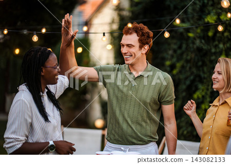 Diverse friends giving high five at outdoor party Diverse friends giving high five at outdoor party 143082133