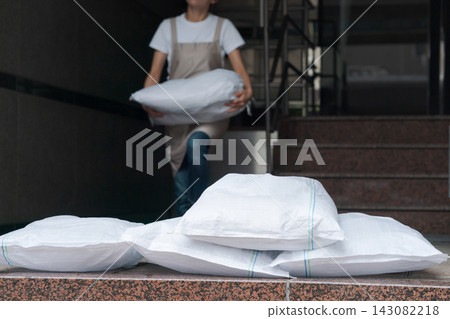 一名女子扛著沙袋站在商店前。 一名女子扛著沙袋站在商店前。 143082218