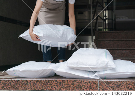 一名女子扛著沙袋站在商店前。 一名女子扛著沙袋站在商店前。 143082219