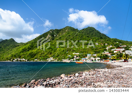 Beautiful coastline of Scotts Head village with lush green mountains and pebble beach along Soufriere Bay in Dominica, Caribbean. Beautiful coastline of Scotts Head village with lush green mountains and pebble beach along Soufriere Bay in Dominica, Caribbean. 143083444