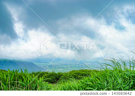 Low clouds and rain clouds approach the green grasslands of the Aso Caldera in Kumamoto Prefecture. Low clouds and rain clouds approach the green grasslands of the Aso Caldera in Kumamoto Prefecture. 143083642