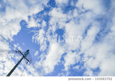 日本的電線桿和電線桿仰望藍天,白雲在空中飄蕩。 日本的電線桿和電線桿仰望藍天,白雲在空中飄蕩。 143083702