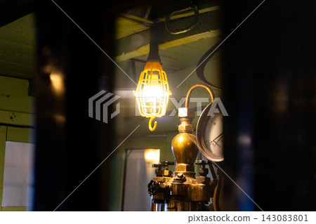 Brass pressure gauges and old machinery illuminated in a dimly lit industrial space Brass pressure gauges and old machinery illuminated in a dimly lit industrial space 143083801