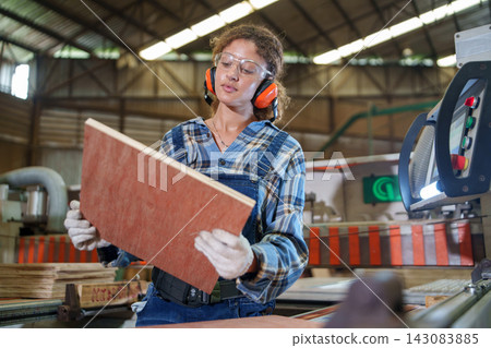 Factory Worker Inspecting Wood Panel on Manufacturing Line Factory Worker Inspecting Wood Panel on Manufacturing Line 143083885