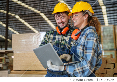 Factory Workers Collaborating on Laptop in Timber Warehouse Factory Workers Collaborating on Laptop in Timber Warehouse 143083926