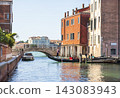 Traditional Gondola on a Quiet Venetian Canal with Historic Bridge in Venice, Italy 143083943