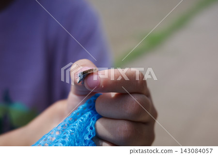 孩子的小手撿起了一隻小蝴蝶和一個藍色的捕蟲網。 孩子的小手撿起了一隻小蝴蝶和一個藍色的捕蟲網。 143084057