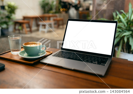 Laptop computer with blank white screen mockup on wooden table in a coffee shop with a cup of latte. Laptop computer with blank white screen mockup on wooden table in a coffee shop with a cup of latte. 143084564