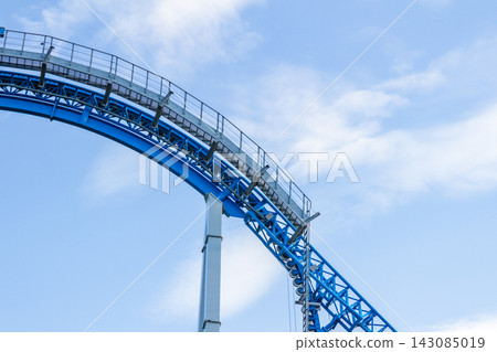 Blue roller coaster track with maintenance walkway against cloudy sky Blue roller coaster track with maintenance walkway against cloudy sky 143085019