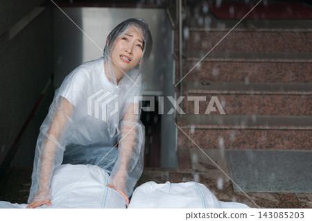 一名婦女正在堆放沙袋,為防洪做準備。 一名婦女正在堆放沙袋,為防洪做準備。 143085203