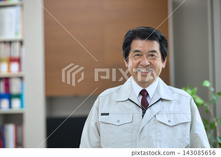 一位身穿工作服的老者面帶微笑。 143085656