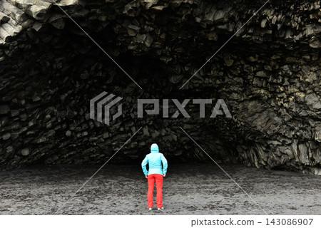 Hiker standing before the dramatic Halsanefshellir basalt cave on Reynisfjara beach Iceland Hiker standing before the dramatic Halsanefshellir basalt cave on Reynisfjara beach Iceland 143086907