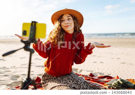 Style woman using smartphone with stabilizer, taking pictures in on sea beach. Woman creates content Style woman using smartphone with stabilizer, taking pictures in on sea beach. Woman creates content 143088043