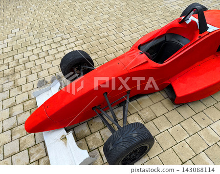 Race car model sits on a stone surface near a pit area in a workshop during daytime Race car model sits on a stone surface near a pit area in a workshop during daytime 143088114