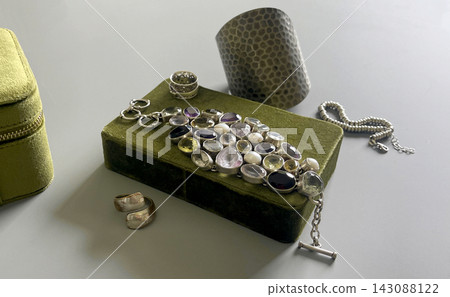 Collection of silver jewelry displayed on a green box in a bright room during the day Collection of silver jewelry displayed on a green box in a bright room during the day 143088122