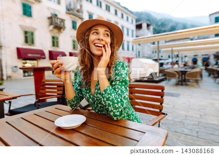 Woman in outdoors street coffee shop cafe sitting at table with cup of coffee. People, fashion Woman in outdoors street coffee shop cafe sitting at table with cup of coffee. People, fashion 143088168