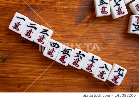 Mahjong tiles on a wood grain background Mahjong tiles on a wood grain background 143088200
