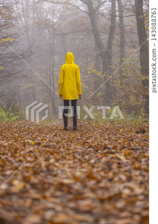 Young woman with yellow raincoat and rubber boots in autumn landscape Young woman with yellow raincoat and rubber boots in autumn landscape 143088761