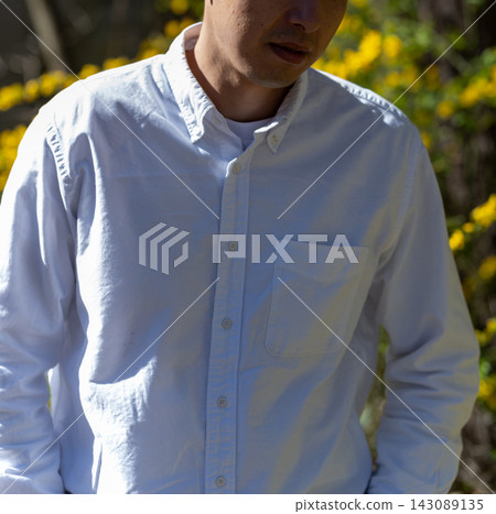 A man in a white shirt stands in nature. A man in a white shirt stands in nature. 143089135