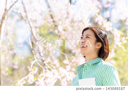 A woman smiling under the cherry blossoms in spring A woman smiling under the cherry blossoms in spring 143089187