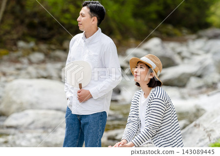 A man and woman relaxing by the river, a summer moment. A man and woman relaxing by the river, a summer moment. 143089445