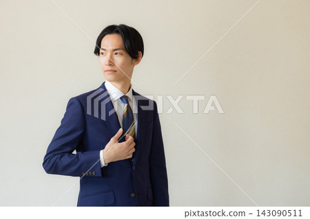 A young man in a suit with his arms crossed A young man in a suit with his arms crossed 143090511