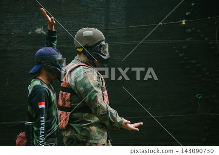 Paintball Players Communicating Tactics Outdoors in Protective Gear Paintball Players Communicating Tactics Outdoors in Protective Gear 143090730