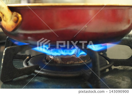 The image shows a pot being heated by the blue flame of a gas stove. It symbolizes rising energy prices, increased gas prices, and the need to save on utility bills, putting pressure on household finances. The image shows a pot being heated by the blue flame of a gas stove. It symbolizes rising energy prices, increased gas prices, and the need to save on utility bills, putting pressure on household finances. 143090900