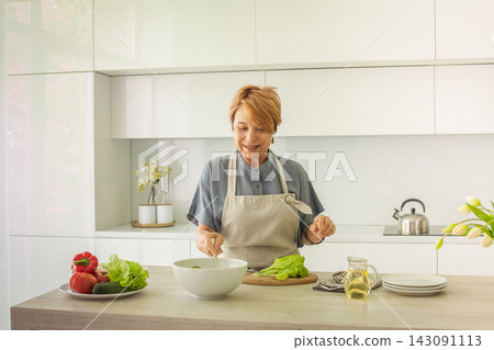 Pretty senior woman chopping and cutting vegetable, making breakfast. Preparation, cookery Pretty senior woman chopping and cutting vegetable, making breakfast. Preparation, cookery 143091113