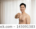 A shirtless Japanese man making a pointing gesture. 143091383