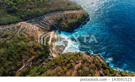 Drone view of rugged green peninsula surrounded by bright blue ocean waves Drone view of rugged green peninsula surrounded by bright blue ocean waves 143091523