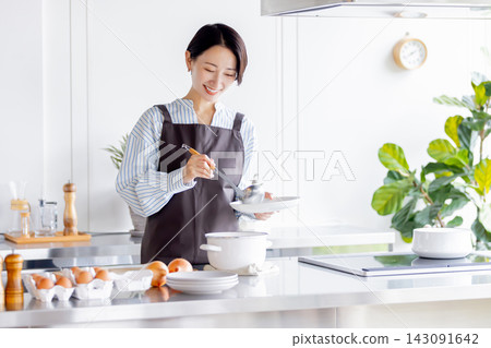 A smiling Japanese female cooking instructor plates food in a bright kitchen. A smiling Japanese female cooking instructor plates food in a bright kitchen. 143091642