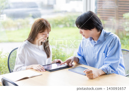 Young Japanese men and women learning together while looking at tablets Young Japanese men and women learning together while looking at tablets 143091657